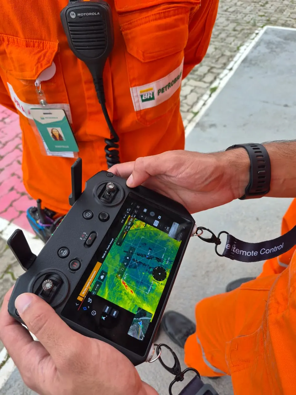 Mãos seguram o controle do drone com a imagem da câmera térmica na tela