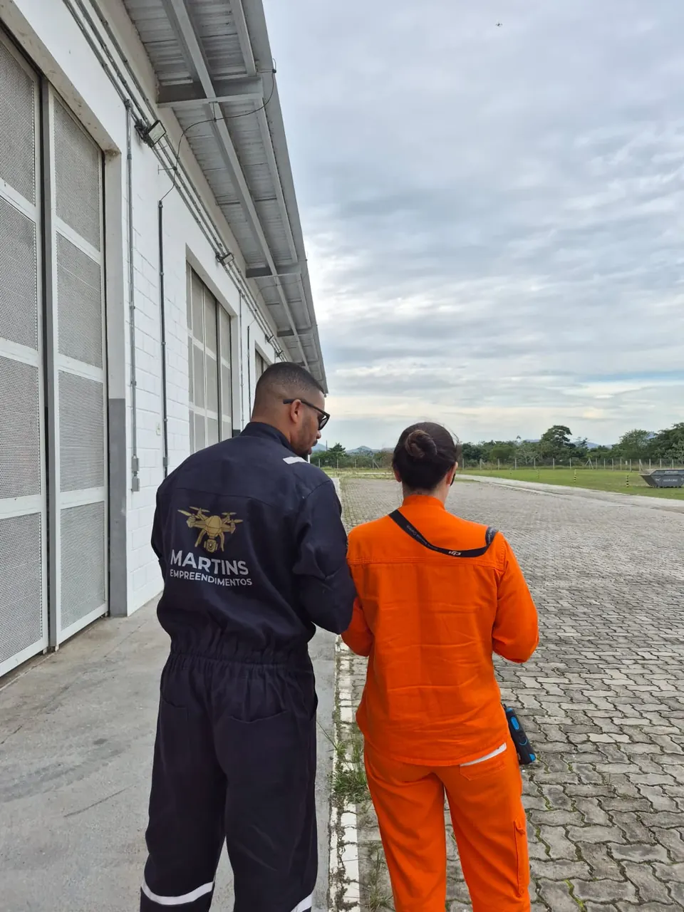 Instrutor com o uniforme da Martins orienta uma aluna durante o voo, vistos de costas