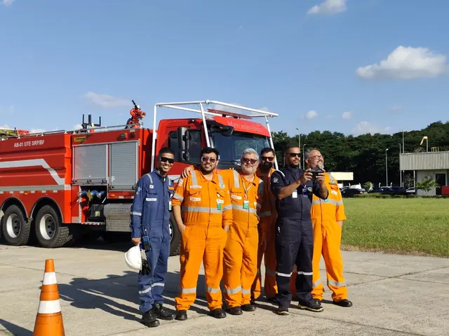 Turma de alunos e instrutores reunida na área externa, ao lado de um caminhão de bombeiros